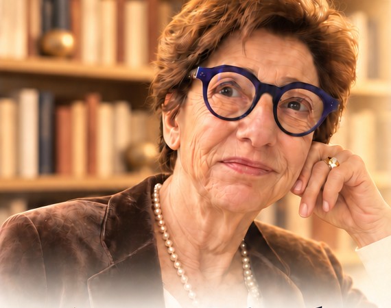 Portrait d’Anne Binder devant une bibliothèque, la main près du visage